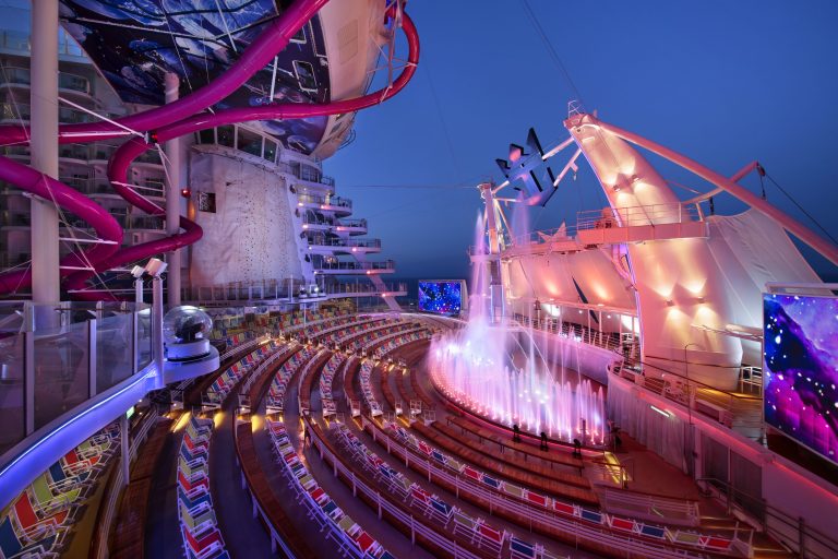 HM, Harmony of the Seas, AquaTheater - Deck 6 Aft, no people, side view of arena, seating, fountains, water, Ultimate Abyss purple slide tubes winding around, stage, movie screens,